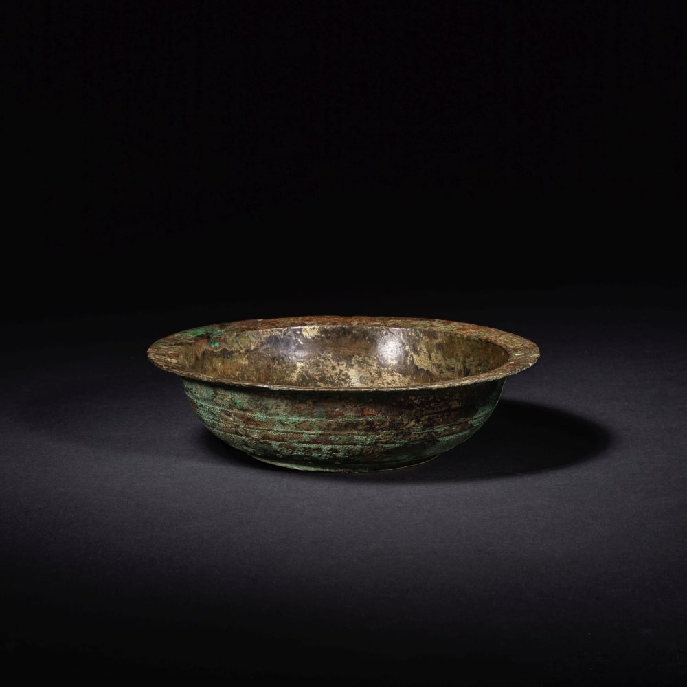 RARE BOL EN BRONZE DORÉ Dynastie Han (206 av. J.-C. - 220 ap. J.-C.): RARE BOL EN BRONZE DORÉ Dynastie Han (206 av. J.-C. - 220 ap. J.-C.) A RARE GILT-BRONZE BOWL Han Dynasty Heavily cast with a flat base and deep rounded sides rising to a flat everted rim, the int