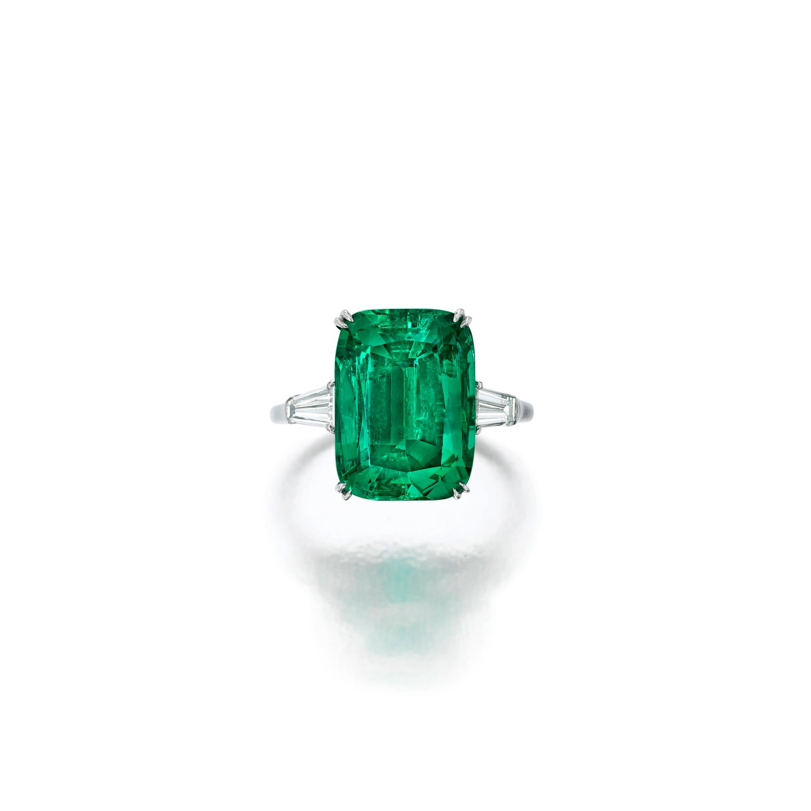 HARRY WINSTON: AN EMERALD AND DIAMOND RING: HARRY WINSTON: AN EMERALD AND DIAMOND RING Centering a cushion-cut emerald, weighing 7.08 carats, flanked by tapered baguette-cut diamonds; signed WINSTON; mounted in platinum; size 6 Footnotes: