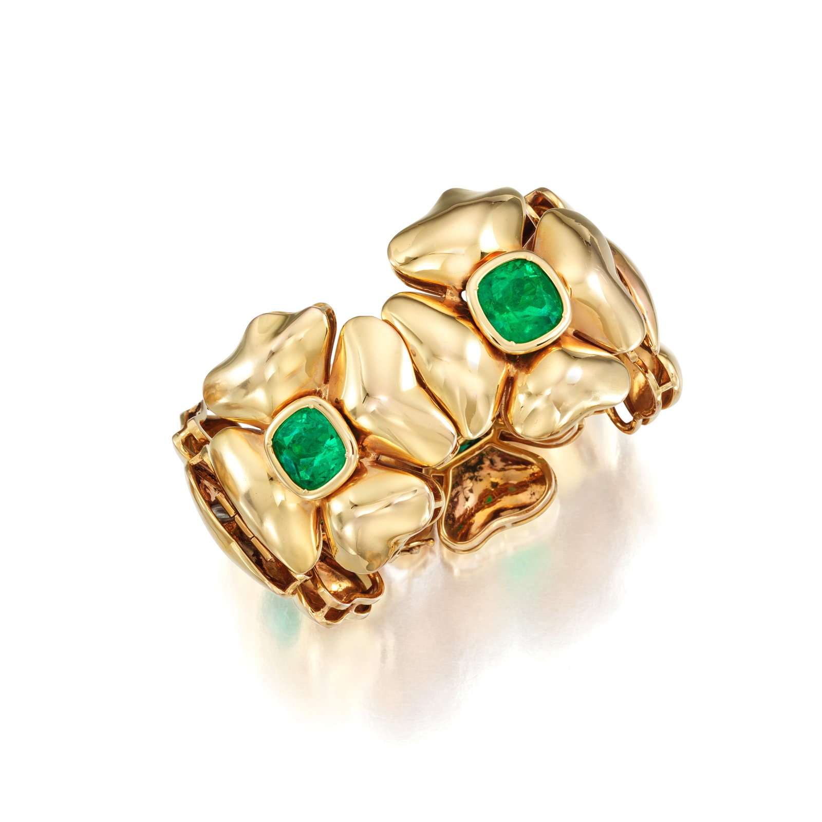 AN EMERALD BRACELET: AN EMERALD BRACELET The bracelet centering five cushion-cut emeralds, each within a quatrefoil flower motif; estimated total emerald weight 30.00 to 35.00 carats; mounted in 18K gold; length 7¼
