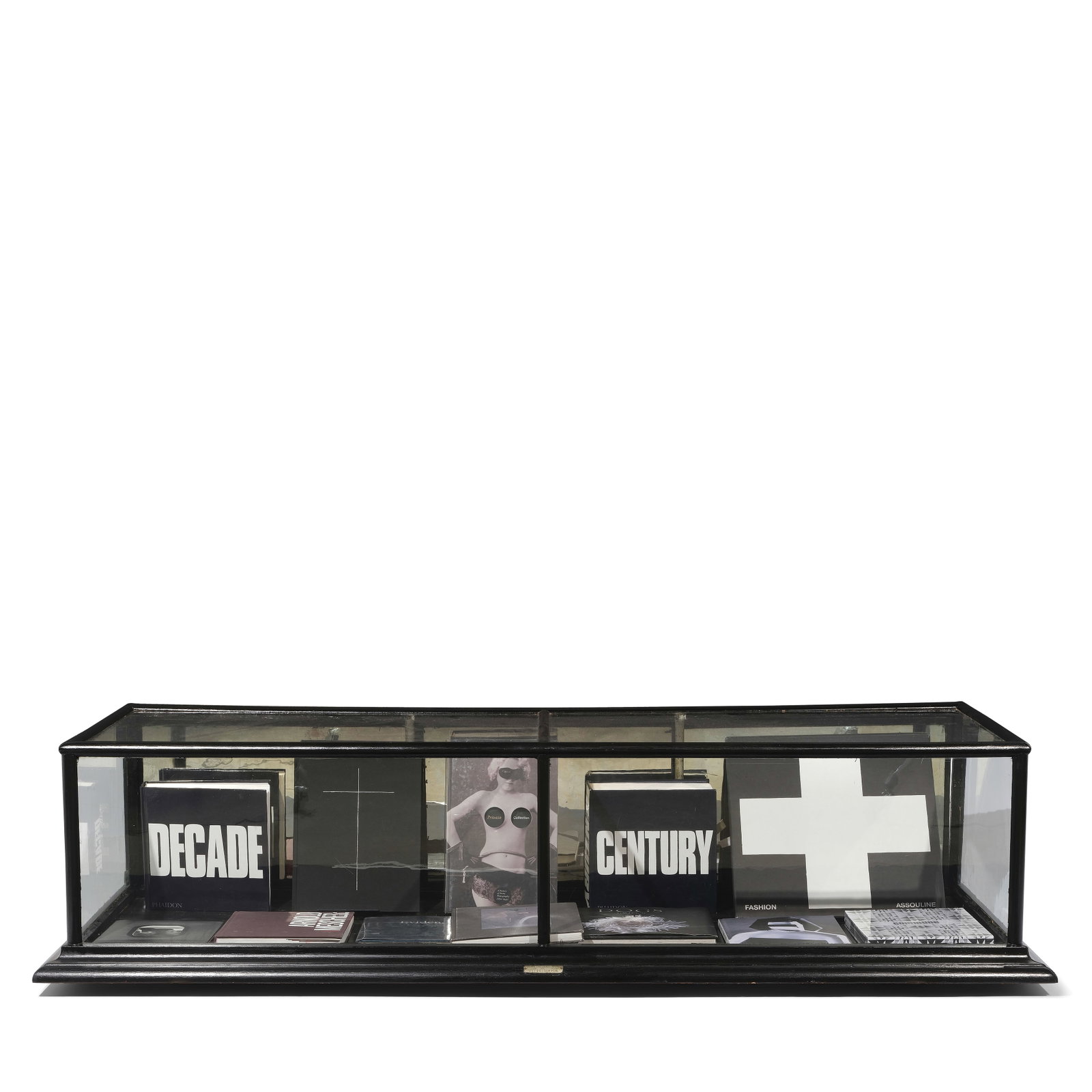 A CURATED GLASS AND BLACK PAINTED WOOD DISPLAY CASE: A CURATED GLASS AND BLACK PAINTED WOOD DISPLAY CASE The display case filled with books including Commune: Designed in California published by Abrams, Century published by Phaidon, and Fashion Assoulin
