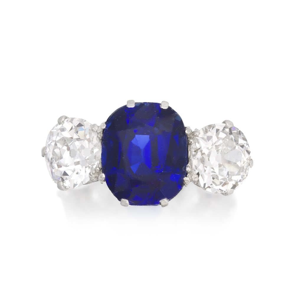 SAPPHIRE AND DIAMOND THREE-STONE RING: SAPPHIRE AND DIAMOND THREE-STONE RING The cushion-cut sapphire, weighing 4.37 carats, between two old brilliant-cut diamonds, weighing 1.27 and 1.29 carats, ring size L Footnotes: Jewels from a