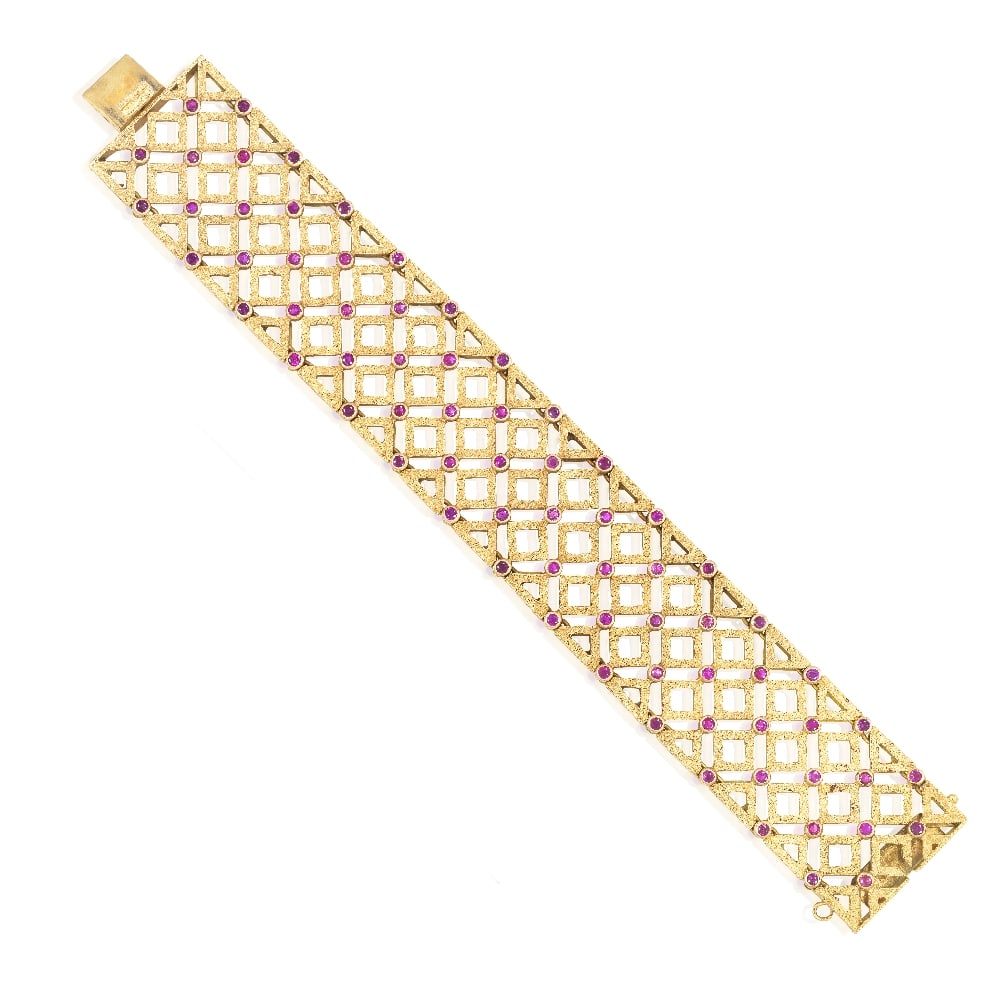 MARIO BUCCELLATI: RUBY STRAP BRACELET: MARIO BUCCELLATI: RUBY STRAP BRACELET The articulated strap of geometric design, with engraved 'ornato' detail, accented by circular-cut rubies, engraved 'rigato' detail to verso, signed