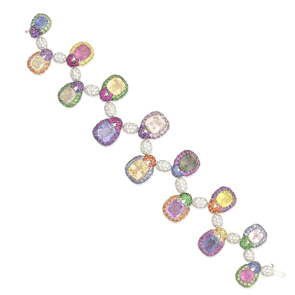DE GRISOGONO: SAPPHIRE, GARNET AND DIAMOND BRACELET: DE GRISOGONO: SAPPHIRE, GARNET AND DIAMOND BRACELET Articulating throughout with fourteen cushion-shaped vari-coloured sapphires, graduating in size towards the centre, within halo surrounds,