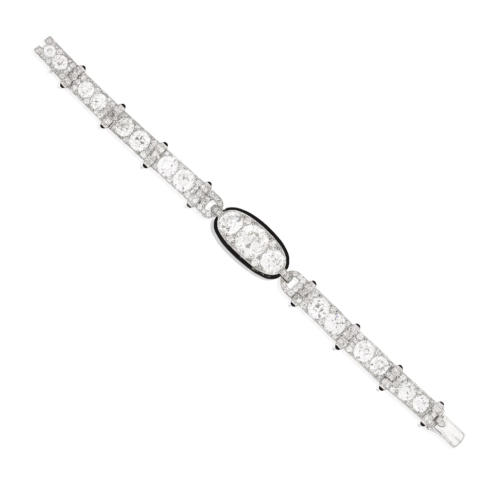 CARTIER: DIAMOND, ONYX AND ENAMEL BRACELET, CIRCA 1925: CARTIER: DIAMOND, ONYX AND ENAMEL BRACELET, CIRCA 1925 The central curved plaque set with an old brilliant-cut diamond, weighing 5.82 carats, between similarly-cut diamond shoulders, within a black