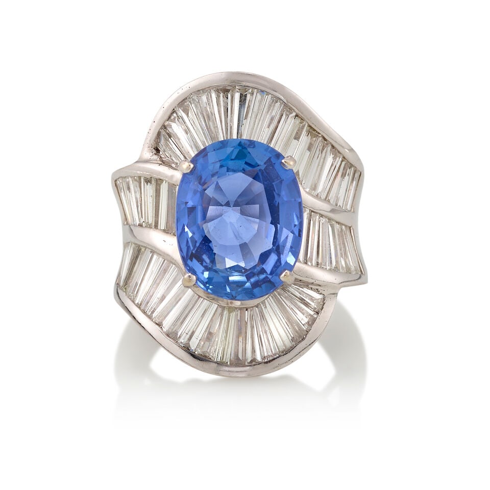 18K GOLD, BERYLLIUM DIFFUSED SAPPHIRE, AND DIAMOND RING WITH GIA REPORT: 18K GOLD, BERYLLIUM DIFFUSED SAPPHIRE, AND DIAMOND RING WITH GIA REPORT • 18K white gold • One oval shaped sapphire measuring 13.08mm x 10.33mm x 6.01mm • Numerous rectangular shaped