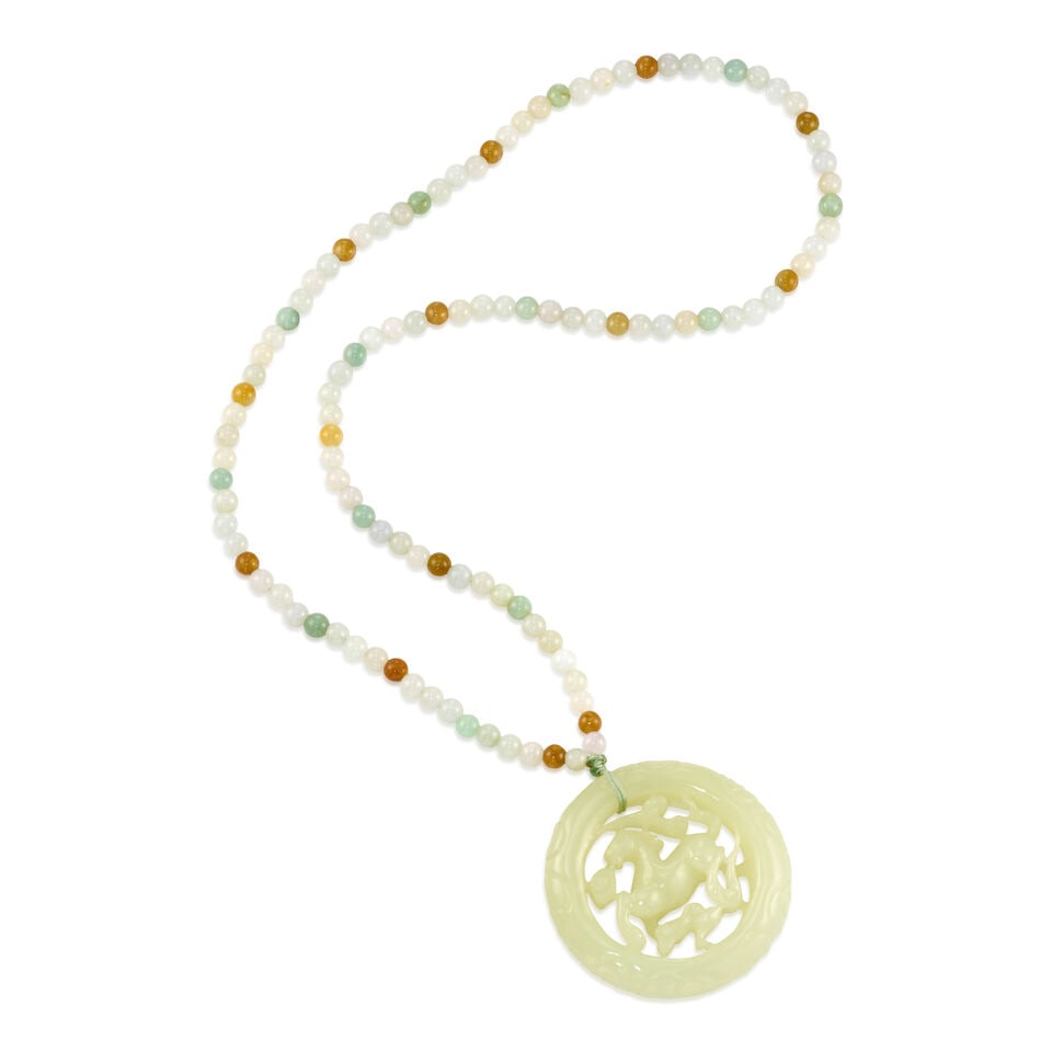 A JADE PENDANT NECKLACE: A JADE PENDANT NECKLACE • One carved jade piece • Numerous jade beads measuring approximately 5.56mm in diameter • Pendant attached with string, measures 2 1/8 in. in diameter •