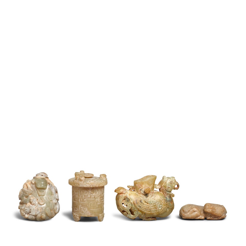 FOUR ARCHAIC-STYLE CELADON JADE CARVINGS 20th century (4, 1 wood stand): FOUR ARCHAIC-STYLE CELADON JADE CARVINGS 20th century Comprising: a 'mythical beast' water coupe and cover; a 'phoenix' vessel; a cylindrical tripod lian and cover; and a recumbent buffalo. Between 5 