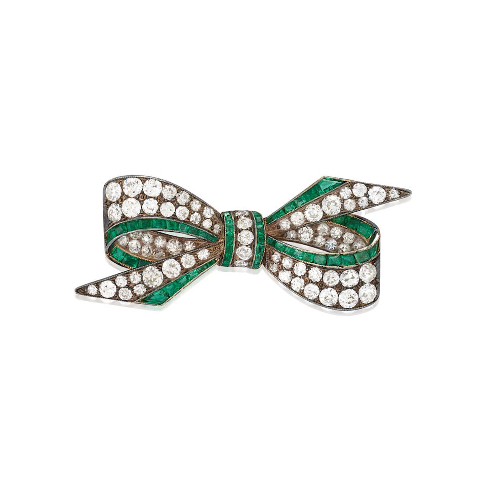 AN ANTIQUE EMERALD AND DIAMOND BOW BROOCH, AUSTRIA-HUNGARY: AN ANTIQUE EMERALD AND DIAMOND BOW BROOCH, AUSTRIA-HUNGARY Designed as a bow set with old European and single-cut diamonds, approximate total weight 2.55 carats, bordered by calibré-cut