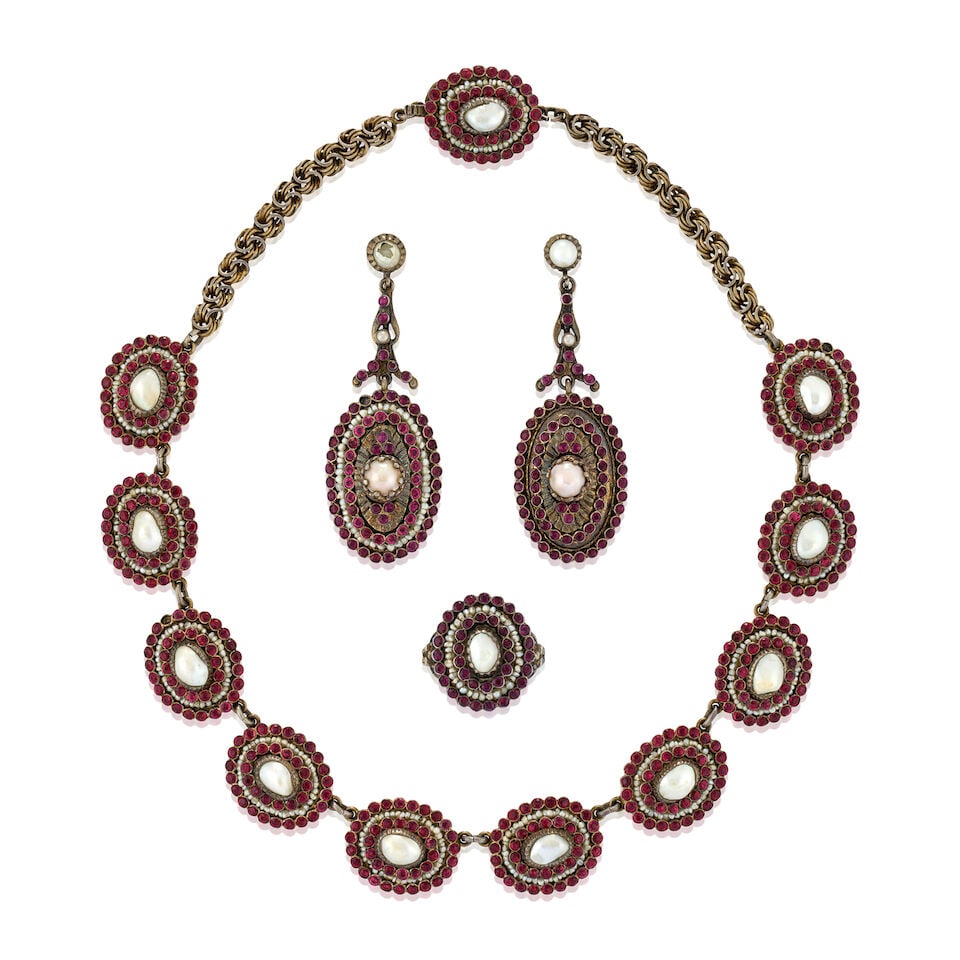 AN ANTIQUE JEWELRY SUITE: AN ANTIQUE JEWELRY SUITE Comprising a necklace, ring, and pair of earclips, each set with baroque freshwater pearls, seed pearls, and red pastes, in closed engraved gilt metal backs, boxed, necklace l