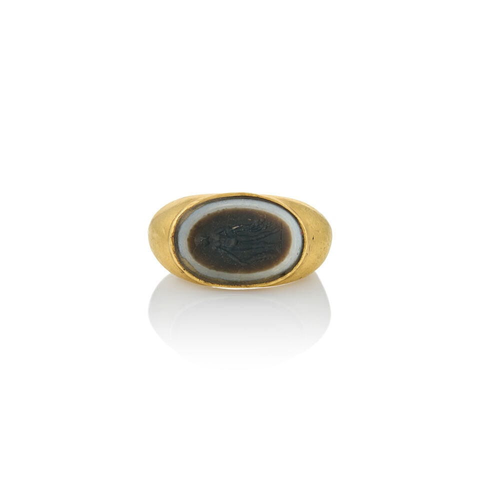 AN ANTIQUE HIGH KARAT GOLD AND HARDSTONE INTAGLIO RING: AN ANTIQUE HIGH KARAT GOLD AND HARDSTONE INTAGLIO RING Centering a hardstone intaglio depicting a nude, bezel-set in a shaped high karat gold mount, weight 14.5 dwt, approximately size 7 1/2. For furt