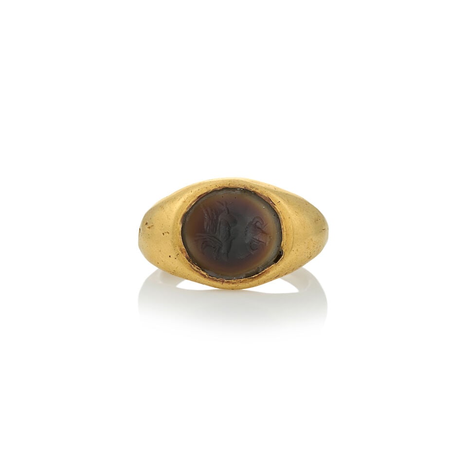 AN ANTIQUE HIGH KARAT GOLD AND HARDSTONE INTAGLIO RING: AN ANTIQUE HIGH KARAT GOLD AND HARDSTONE INTAGLIO RING Centering a hardstone intaglio depicting Pegasus and an ox head, bezel-set in a shaped high karat gold mount, weight 4.9 dwt, approximately size 