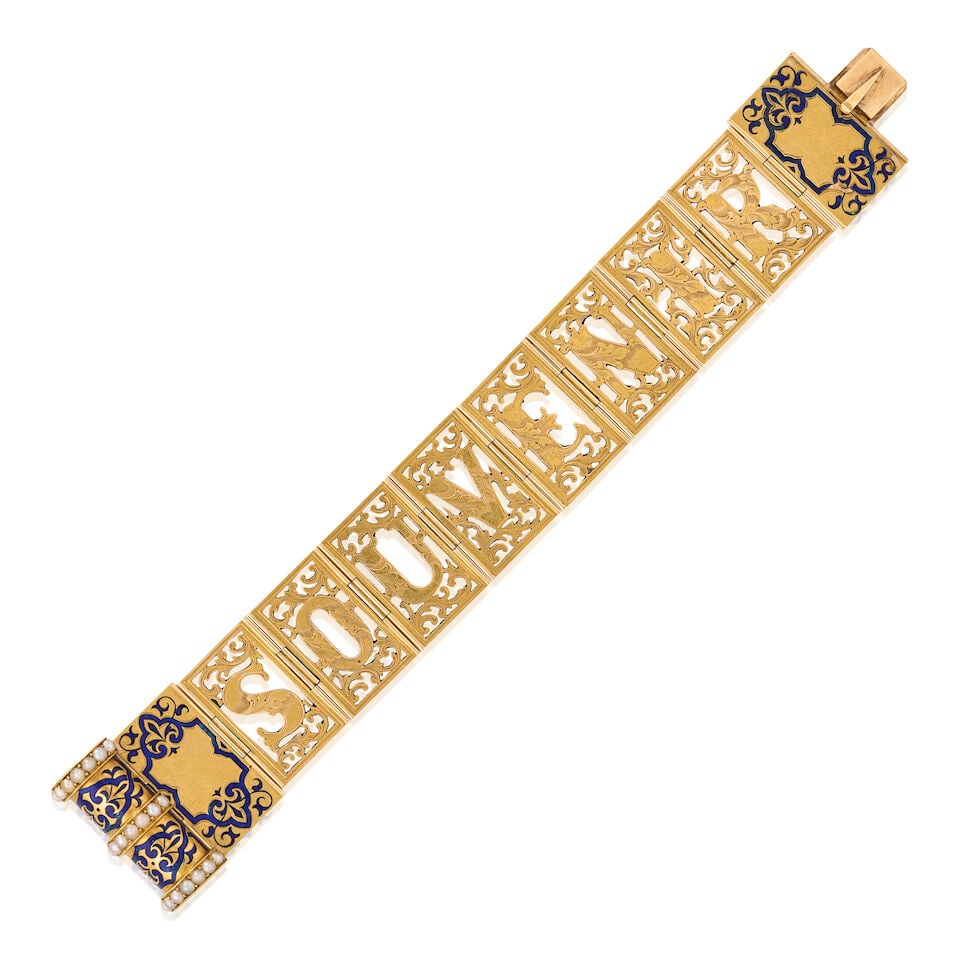 A VICTORIAN GOLD, ENAMEL, AND SPLIT PEARL 'SOUVENIR' BOOK BRACELET: A VICTORIAN GOLD, ENAMEL, AND SPLIT PEARL 'SOUVENIR' BOOK BRACELET Designed as a miniature book, unfolding to reveal hinged, openwork links spelling 'Souvenir' with engraved foliate motifs, the books'