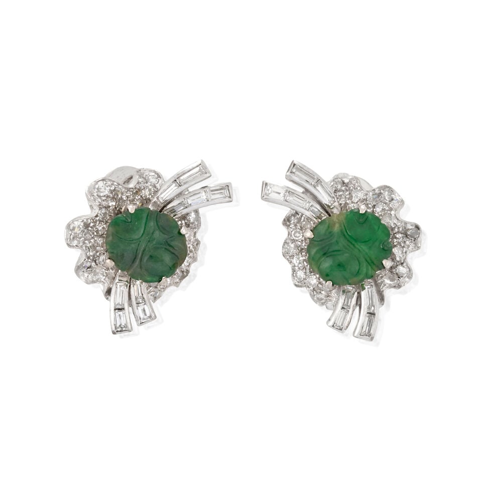 A PAIR OF WHITE GOLD, JADE, AND DIAMOND EARRINGS, CIRCA 1950s: A PAIR OF WHITE GOLD, JADE, AND DIAMOND EARRINGS, CIRCA 1950s Designed as stylized flowers, each centering a carved jade disc with single-cut and baguette-cut diamond petals, approximate total