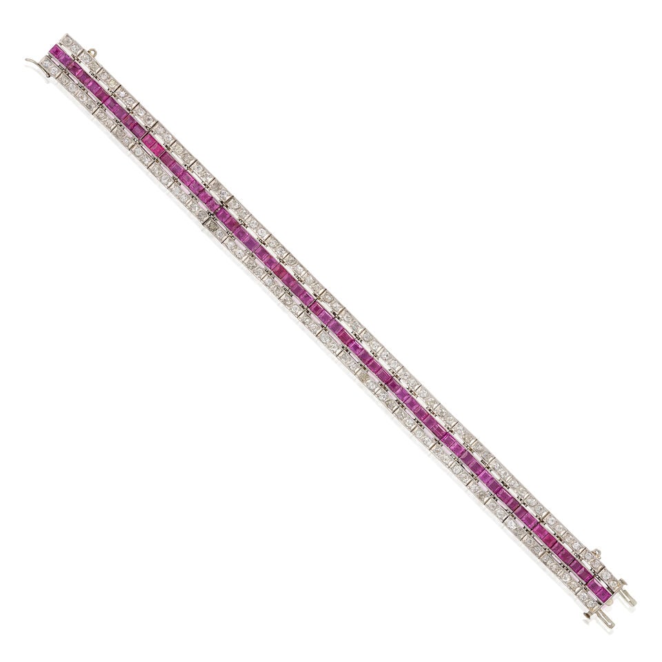 AN ART DECO PLATINUM, RUBY, AND DIAMOND BRACELET: AN ART DECO PLATINUM, RUBY, AND DIAMOND BRACELET Centering a row of channel-set fancy-cut rubies, bordered by rows of old mine and old single-cut diamonds, approximate total diamond weight 2.50