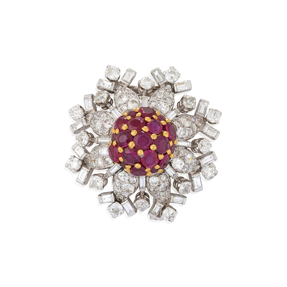 A PLATINUM, RUBY, AND DIAMOND BROOCH, CIRCA 1950s: A PLATINUM, RUBY, AND DIAMOND BROOCH, CIRCA 1950s Designed as a snowflake with a domed circular-cut ruby center, in 18k gold, framed by old European, old single, full, and baguette-cut diamonds,