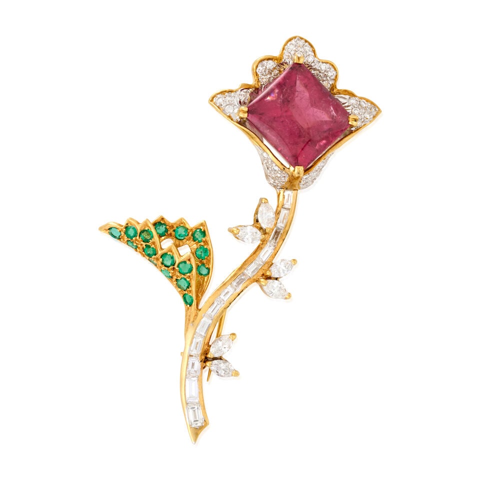 AN 18K GOLD, PINK TOURMALINE, EMERALD, AND DIAMOND FLOWER BROOCH: AN 18K GOLD, PINK TOURMALINE, EMERALD, AND DIAMOND FLOWER BROOCH The stylized flower centering a rectangular buff-top pink tourmaline, measuring approximately 12.75 x 11.90 x 7.80 mm, with full-cut