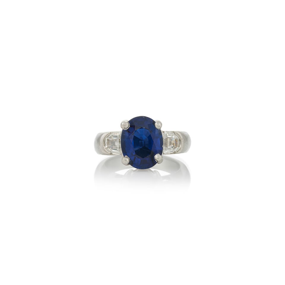 A PLATINUM, SAPPHIRE, AND DIAMOND RING: A PLATINUM, SAPPHIRE, AND DIAMOND RING Centering an oval-cut sapphire measuring approximately 11.75 x 9.30 x 5.20 mm, flanked by half-moon diamonds, weight 10.5 dwt, size 6. Footnotes: Accompanied by