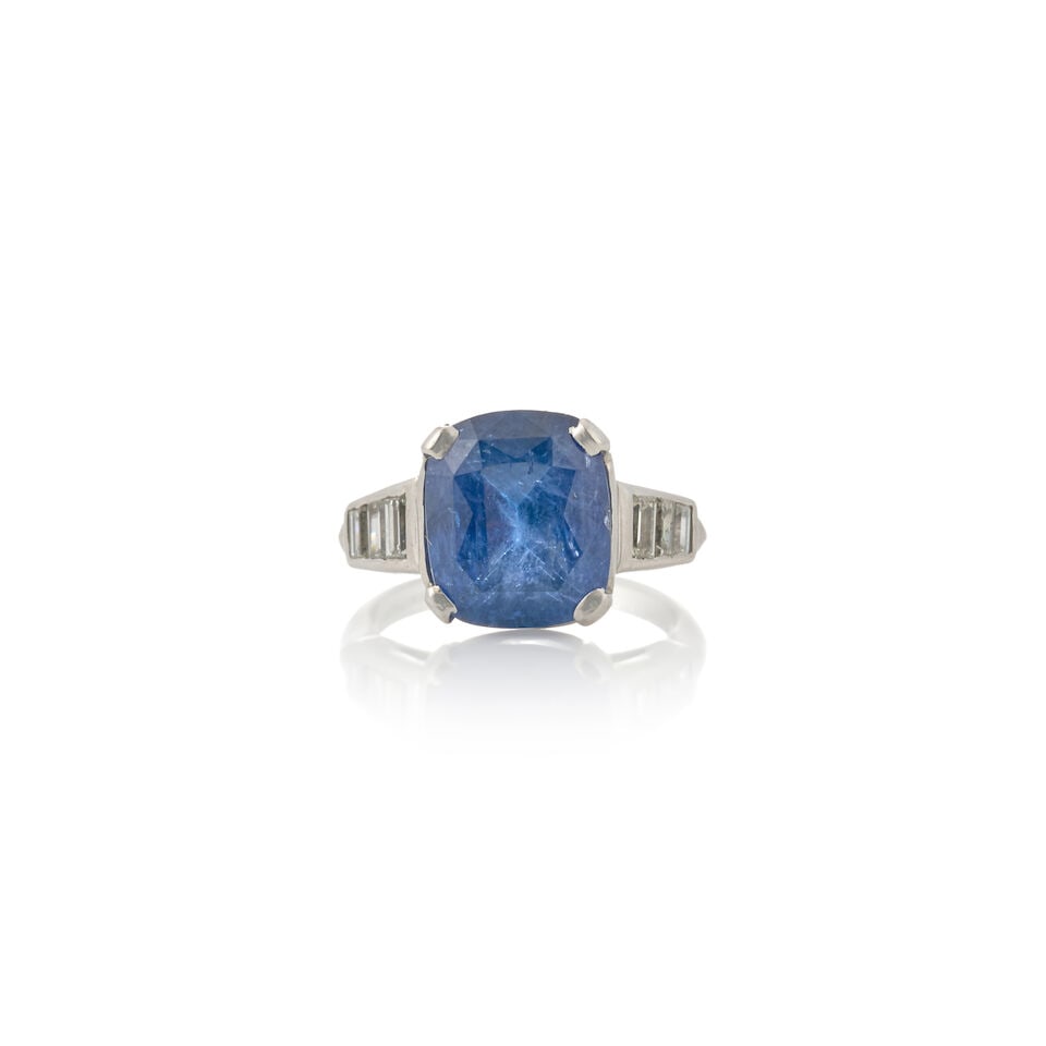 A PLATINUM, SAPPHIRE, AND DIAMOND RING: A PLATINUM, SAPPHIRE, AND DIAMOND RING Centering a fancy-cut sapphire measuring approximately 11.65 x 9.75 x 6.70 mm, with channel-set baguette-cut diamond shoulders, weight 5.0 dwt, size 5 1/4. For f