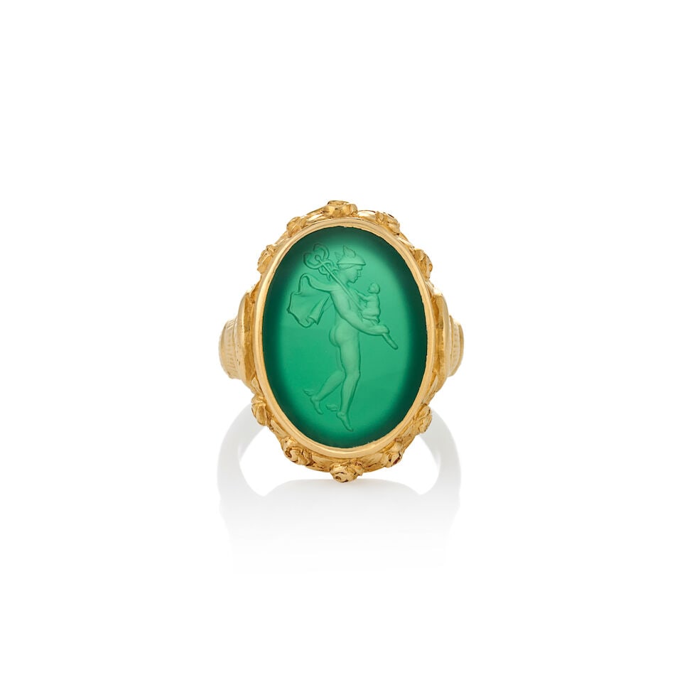 AN 18K GOLD AND INTAGLIO RING: AN 18K GOLD AND INTAGLIO RING The dyed green chalcedony intaglio depicting Hermes with infant Dionysus, bezel-set in an engraved floral mount, weight 9.1 dwt, size 6 1/2. For further information on th