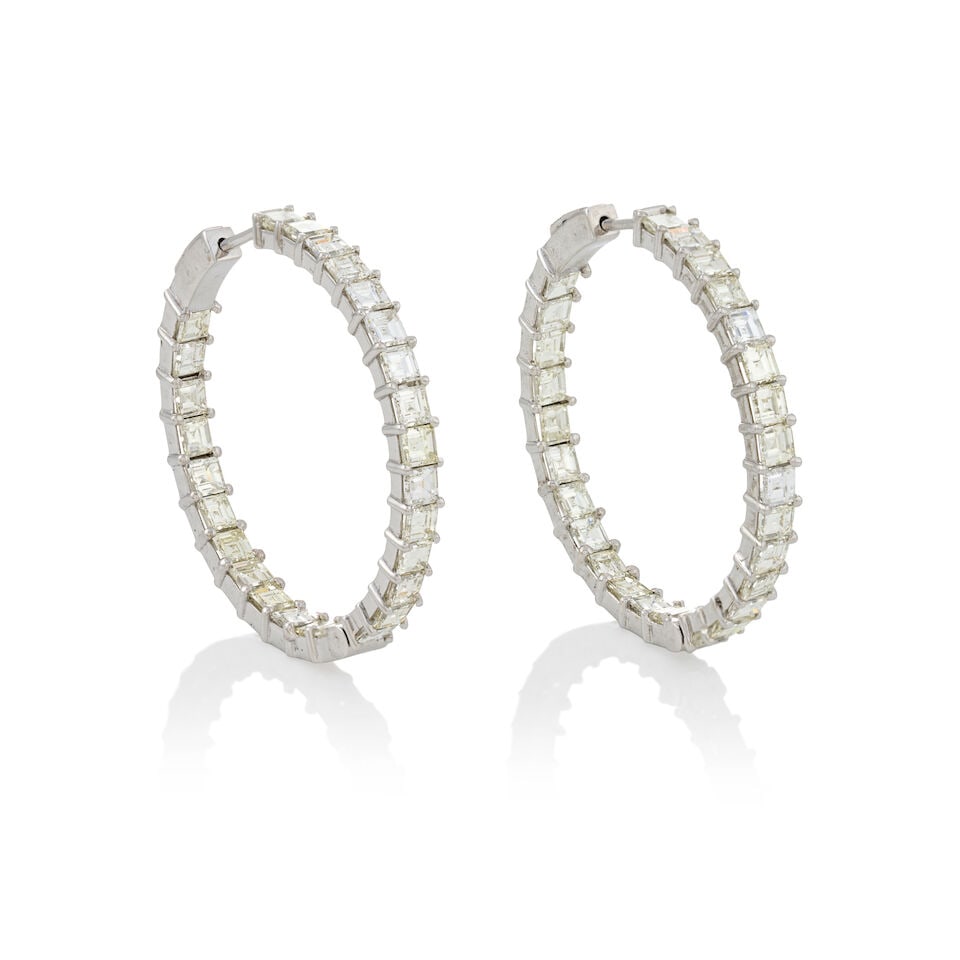 A PAIR OF 14K WHITE GOLD AND DIAMOND HOOP EARRINGS: A PAIR OF 14K WHITE GOLD AND DIAMOND HOOP EARRINGS Set with rectangular step-cut diamonds, total weight 10.99 carats, weight 9.2 dwt, length 1 1/2 in. For further information on this lot please visit