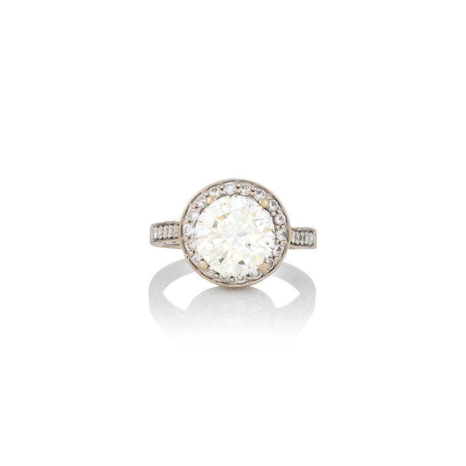 A DIAMOND SOLITAIRE: A DIAMOND SOLITAIRE Centering a round brilliant-cut diamond weighing 3.98 carats, framed by full-cut diamonds, mounted in 18k white gold, weight 4.8 dwt, size 8 3/4. Footnotes: Accompanied by a GIA