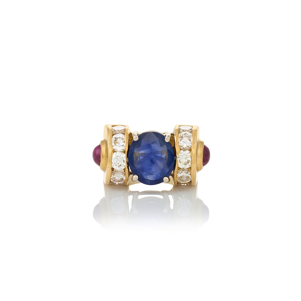 AN 18K GOLD, SAPPHIRE, RUBY, AND DIAMOND RING: AN 18K GOLD, SAPPHIRE, RUBY, AND DIAMOND RING Centering a fancy-cut sapphire measuring approximately 10.75 x 9.20 x 3.65 mm, flanked by rows of channel-set full-cut diamonds, approximate total