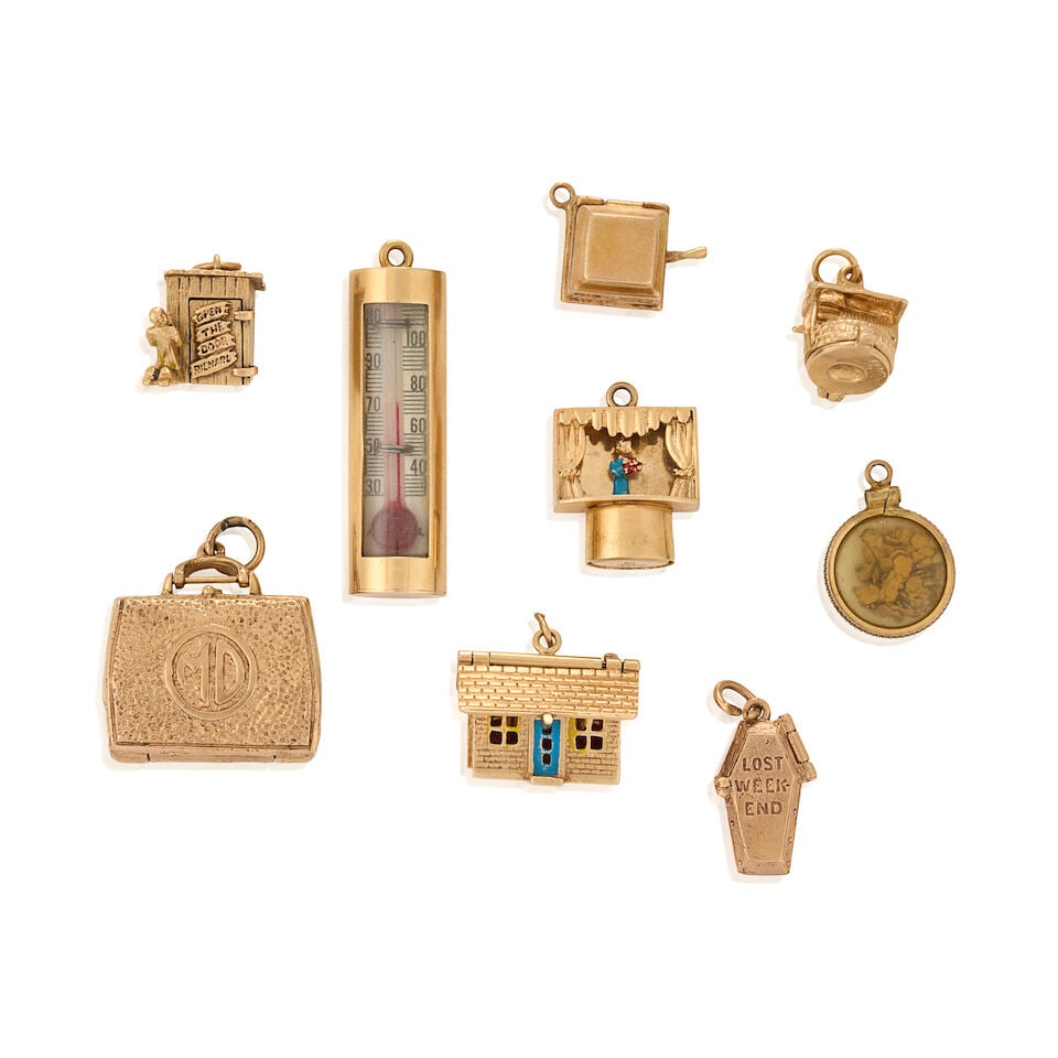 A GROUP OF MOSTLY 14K GOLD CHARMS: A GROUP OF MOSTLY 14K GOLD CHARMS Mostly mechanical charms, including a charm designed as a well with hinged base opening to reveal a cat, an outhouse opening to reveal a person within, a charming hou