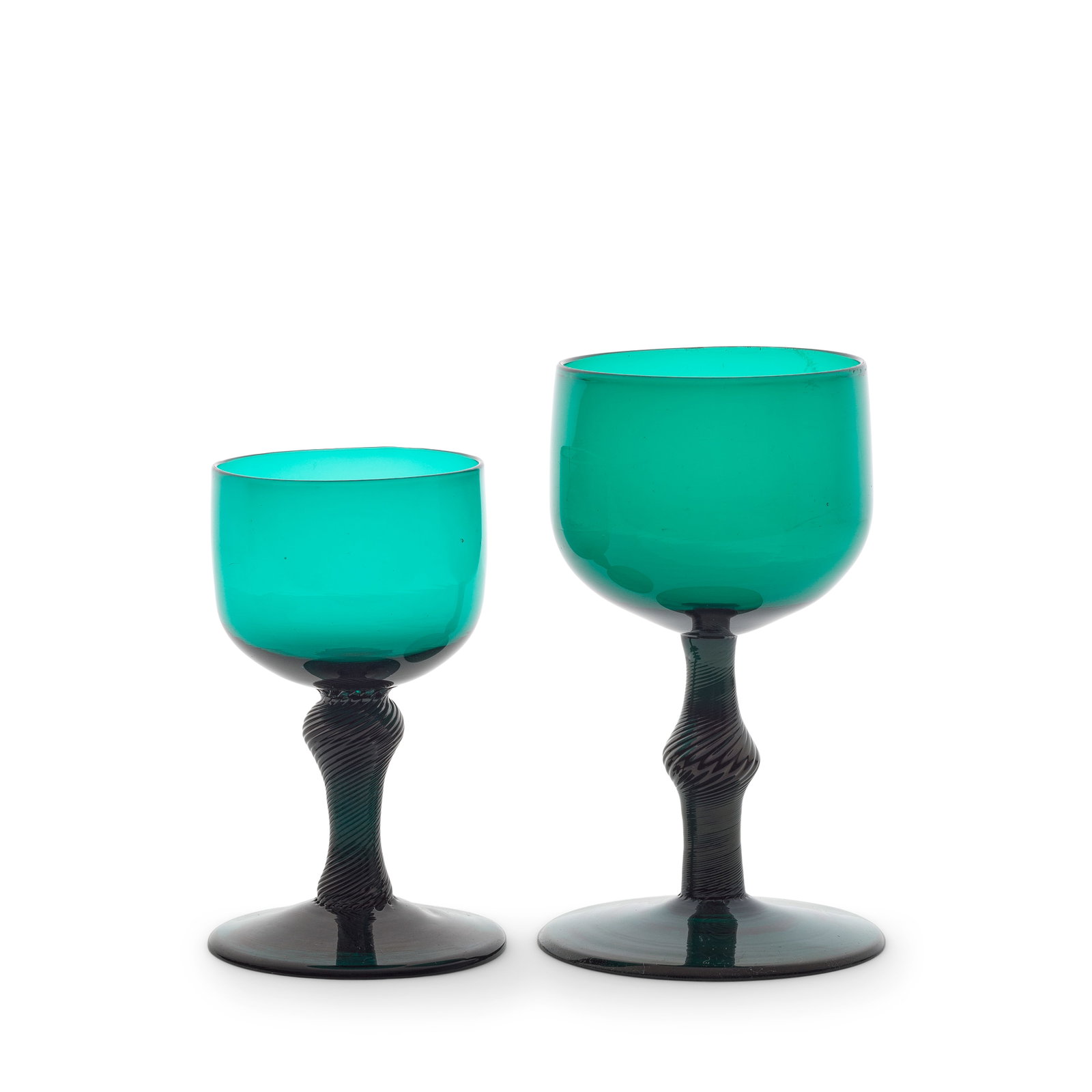 Two emerald-green tinted incised twist wine or champagne glasses, circa 1750-60: Two emerald-green tinted incised twist wine or champagne glasses, circa 1750-60 In deep green glass with cup-shaped bowls, one set on an inverted baluster stem, the other on a stem with a central angu