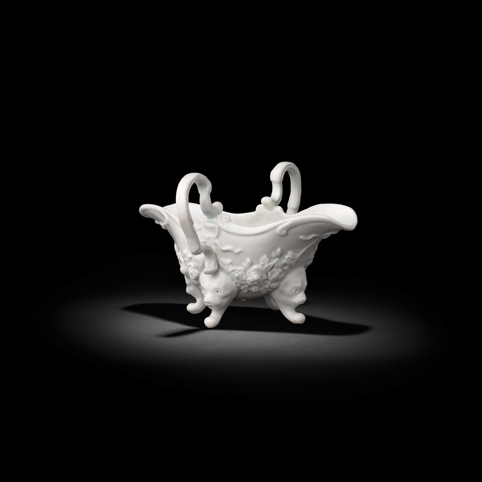 An extraordinary Bow sauceboat, circa 1749-50: An extraordinary Bow sauceboat, circa 1749-50 Of double-lipped form with delicate high scrolled twin handles and raised on four lion mask and paw feet, the exterior moulded in high relief with floral 