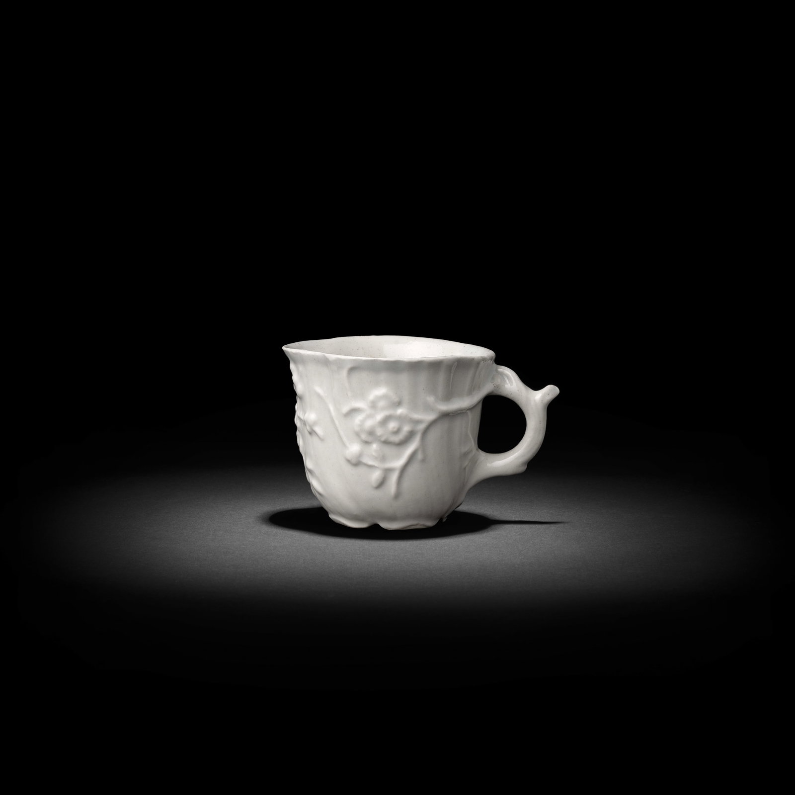 A Limehouse cup, circa 1746-48: A Limehouse cup, circa 1746-48 Of spirally writhed quatrelobed form with a naturalistic stalk handle issuing moulded prunus encircling the form, left in the white, 6.3cm high Footnotes: Provenance Mrs