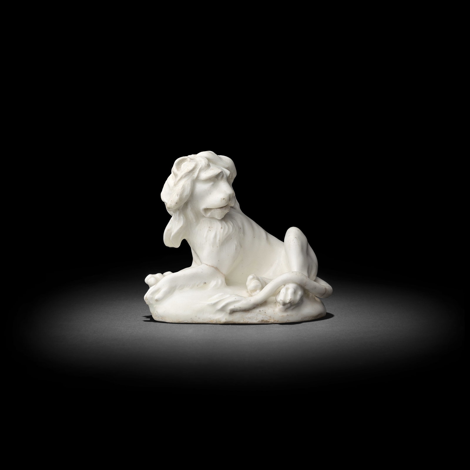 A good Derby 'Dry Edge' model of a lion, circa 1752-55: A good Derby 'Dry Edge' model of a lion, circa 1752-55 The animal recumbent on an oval mound, his expressive face revealed beneath a shaggy mane and his long tail languidly draped over one hind paw, 1