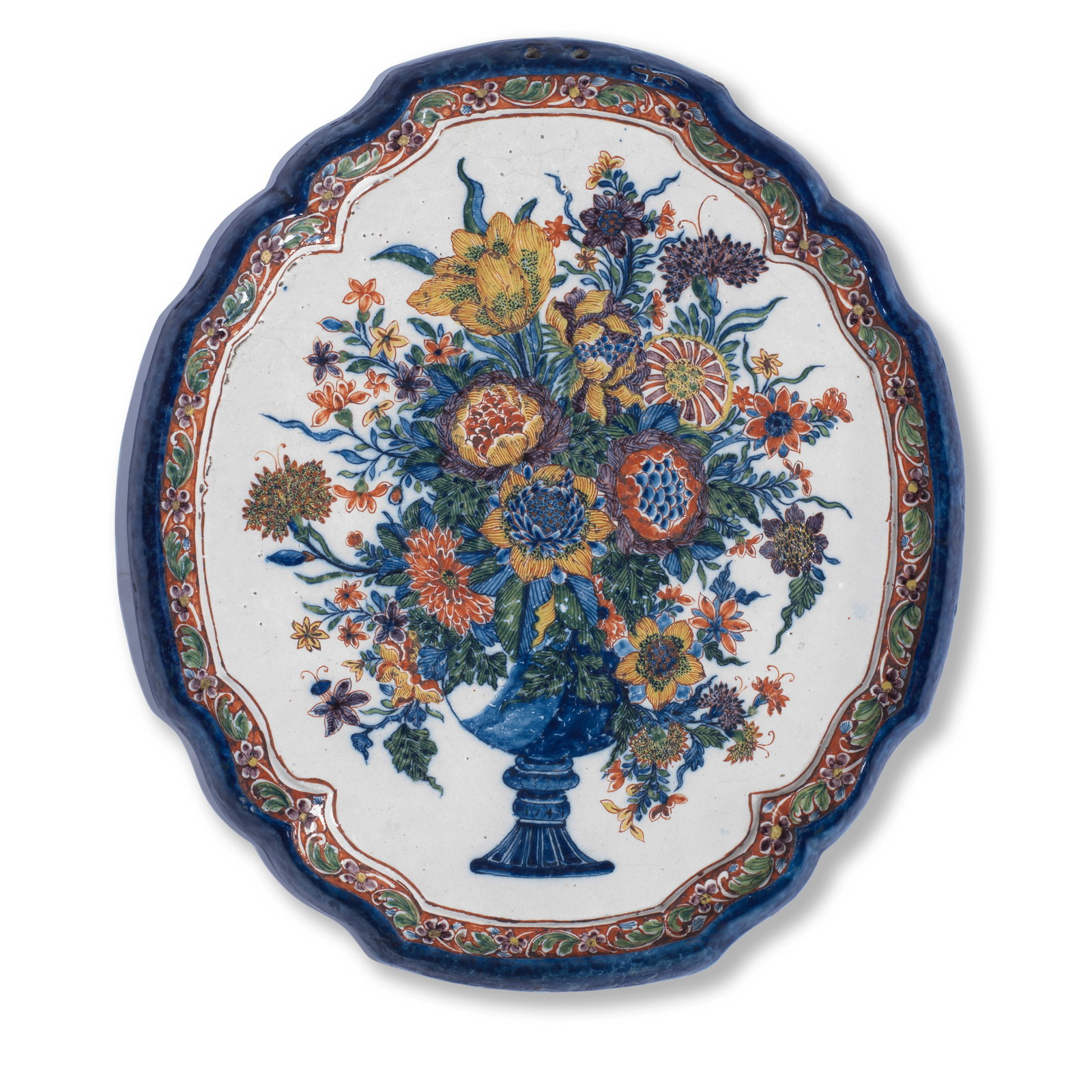 A Dutch Delft plaque, second half 18th century: A Dutch Delft plaque, second half 18th century Of shaped oval form, painted with a large flower bouquet in a vase, the moulded rim with a border of scrolling flowers and foliage on a red ground above 