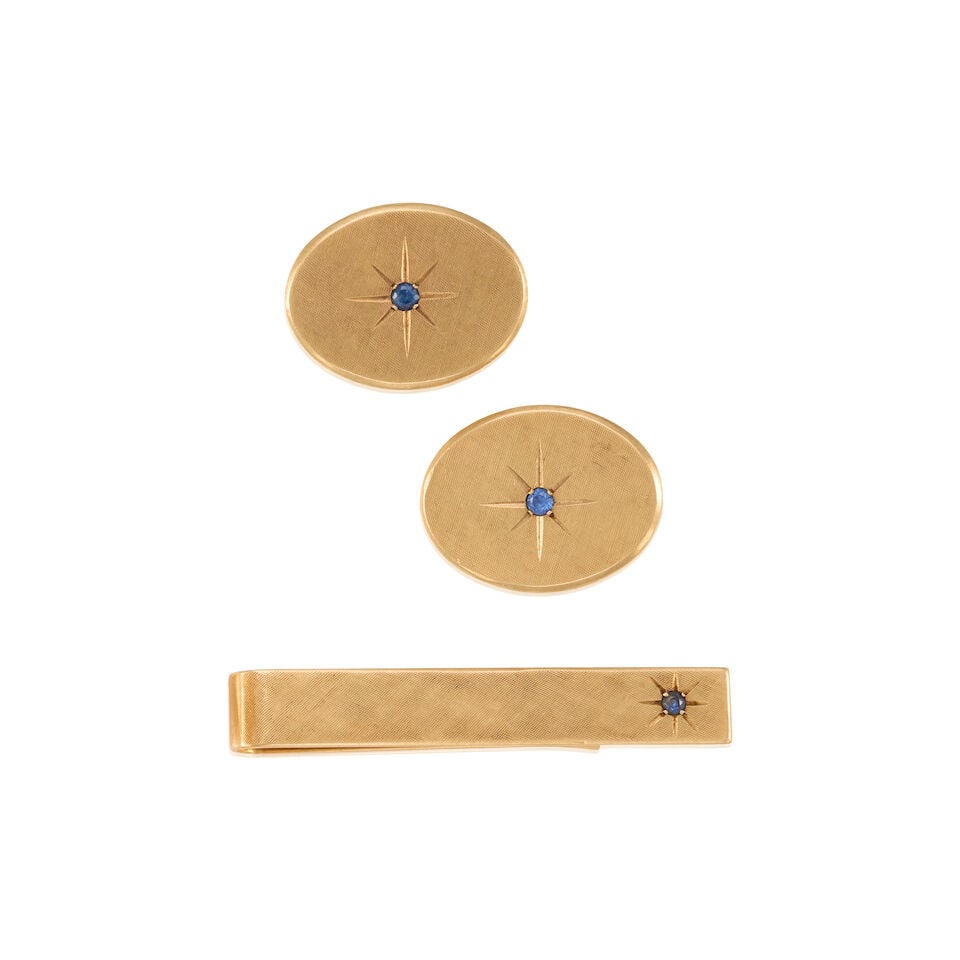 TIFFANY & CO.: 14K YELLOW GOLD AND SAPPHIRE DRESS SET: TIFFANY & CO.: 14K YELLOW GOLD AND SAPPHIRE DRESS SET • One 14K yellow gold tie clip with a round shaped sapphire weighing approximately 0.02 carat, stamped TIFFANY & CO., measures 13/16 in. x 5