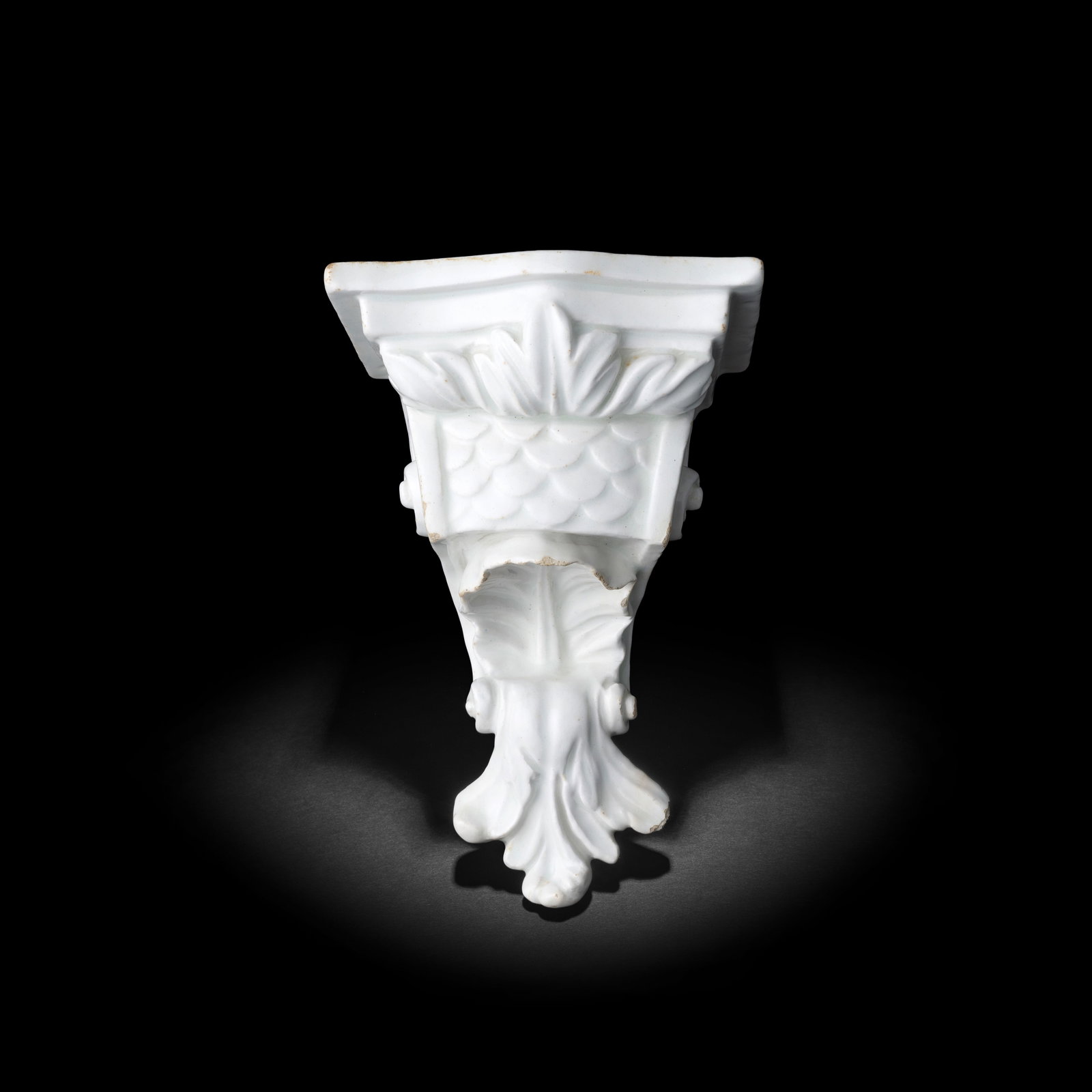 A rare Bow white wall bracket, circa 1755-58: A rare Bow white wall bracket, circa 1755-58 Moulded with acanthus leaves and scale ornament, rococo scrolls to the sides, the rectangular top with a serpentine front and pierced with two holes for su
