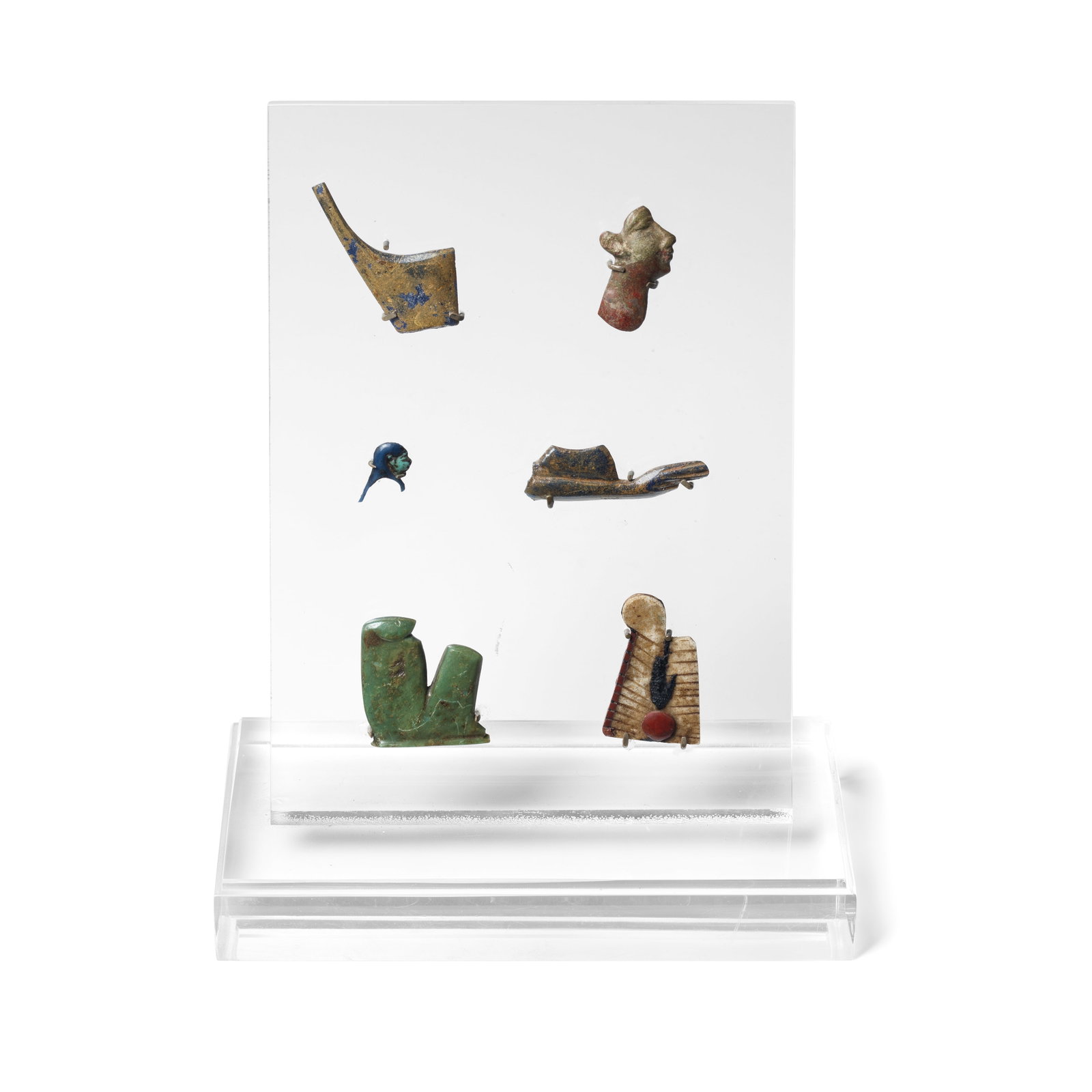Six Egyptian glass and hardstone inlays 6: Six Egyptian glass and hardstone inlays Circa 5th-1st Century B.C. Including the Red Crown of Lower Egypt, a head in profile, a bust of Imsety, an extended arm, a crouching figure, and a double plumed