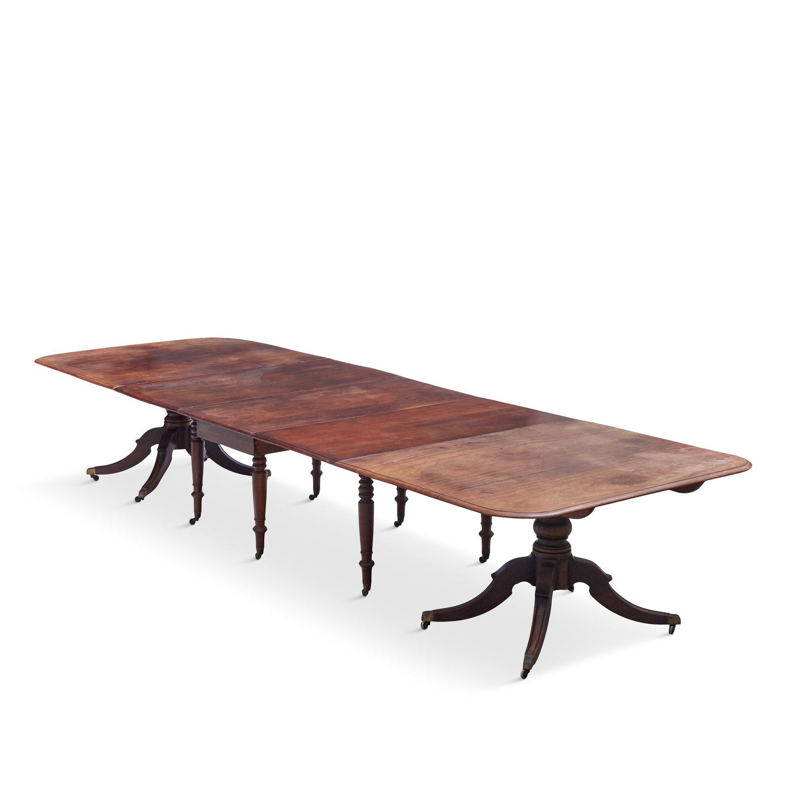 A George III mahogany twin pedestal dining table Fourth quarter 18th century: A George III mahogany twin pedestal dining table Fourth quarter 18th century On turned supports and four down-swept legs with brass caps and castors, together with a drop-leaf central section (possibl