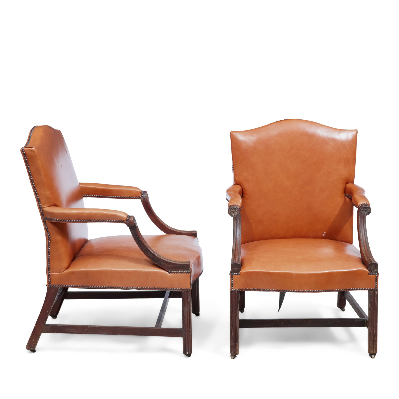 A pair of George III mahogany Gainsborough type armchairs Early 19th century (2): A pair of George III mahogany Gainsborough type armchairs Early 19th century Upholstered in close nailed tan leather with scrolled arms terminating in patera on moulded square chamfered front legs uni