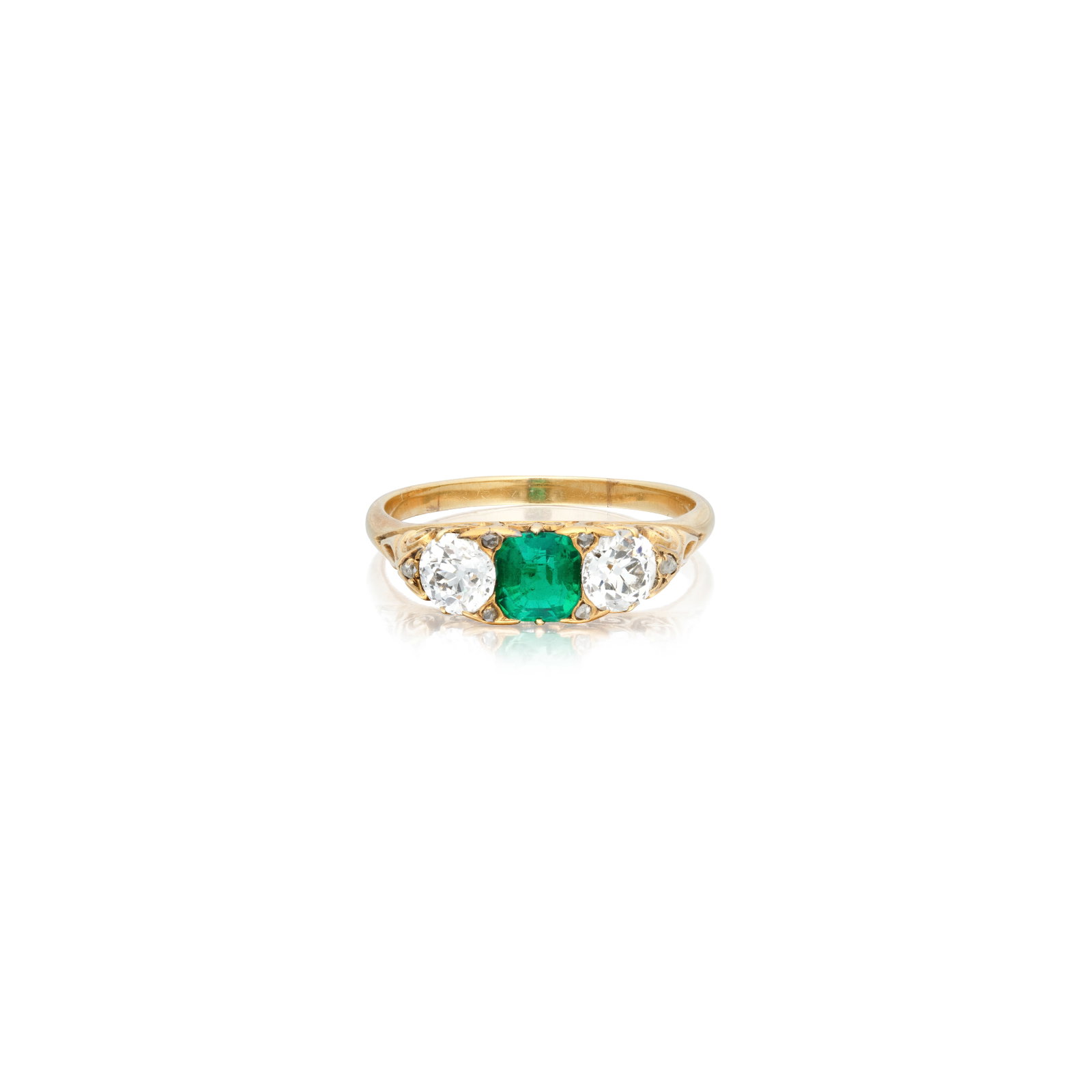 EMERALD AND DIAMOND THREE-STONE RING, CIRCA 1890: EMERALD AND DIAMOND THREE-STONE RING, CIRCA 1890 The octagonal-cut emerald between two old brilliant-cut diamonds, accented by rose-cut diamonds, to a carved scroll gallery, mounted in gold, diamonds 