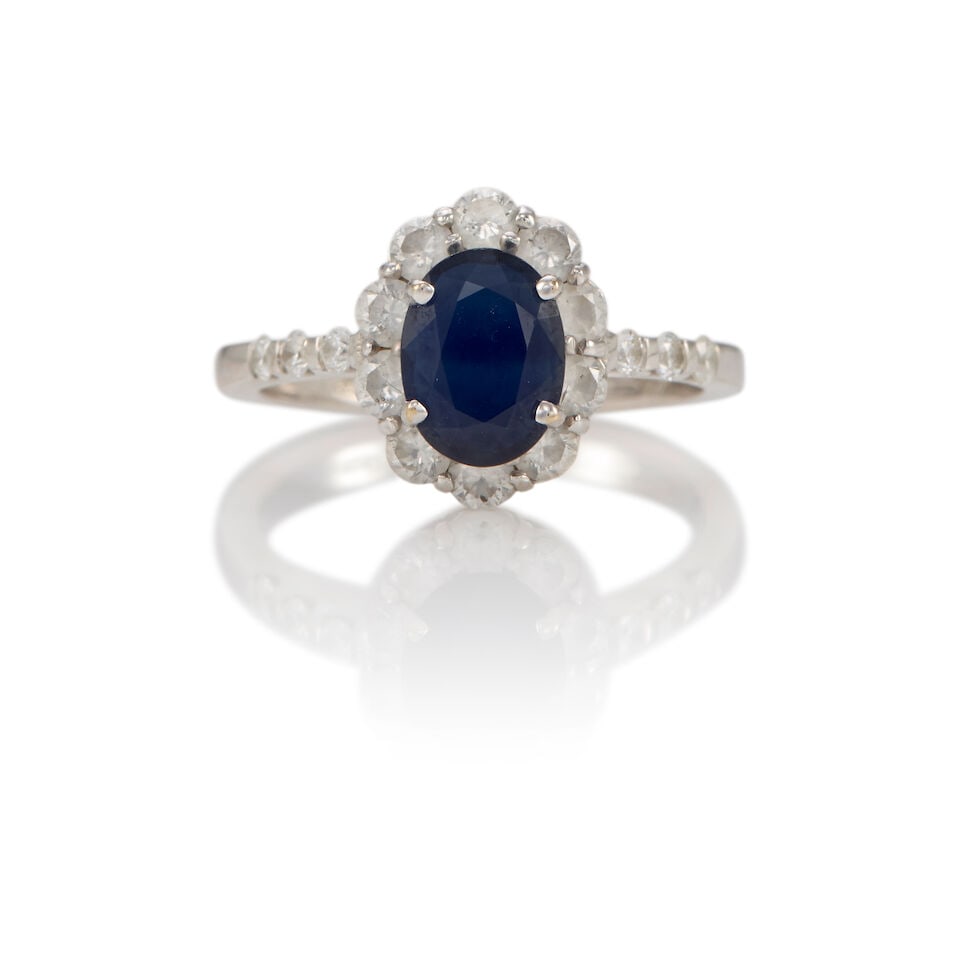 18K WHITE GOLD, SAPPHIRE AND DIAMOND RING: 18K WHITE GOLD, SAPPHIRE AND DIAMOND RING • An oval shaped sapphire weighing approximately 0.85 carat total • Numerous round shaped diamonds weighing approximately 0.55 carat
