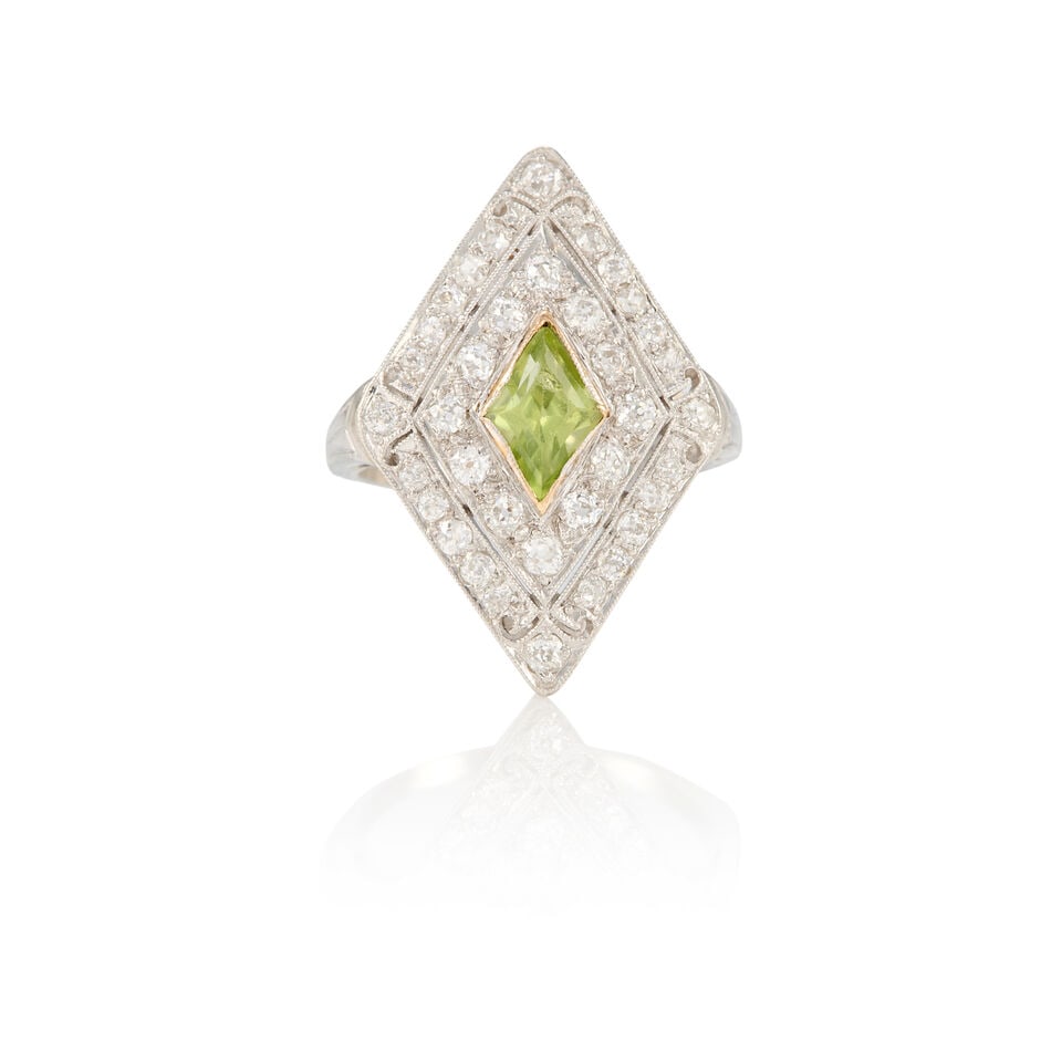 ART DECO PLATINUM, PERIDOT, AND DIAMOND RING: ART DECO PLATINUM, PERIDOT, AND DIAMOND RING • One lozenge shaped peridot weighing approximately 0.70 carats • Numerous round diamonds weighing approximately 0.80 carat total • Size