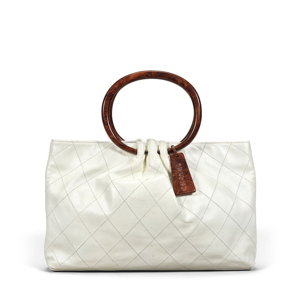 Chanel: a White Tote with Wood-Effect Handles 2000-02 (includes serial sticker, authenticity car...: Chanel: a White Tote with Wood-Effect Handles 2000-02 Creative Director: Karl Lagerfeld Quilted leather tote with burled wood-effect resin ring handles and name tag Condition Grade C- 36cm wide, 24cm 