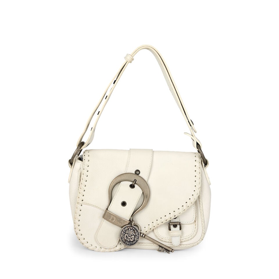 Christian Dior: a White Gaucho Double Saddle 2006: Christian Dior: a White Gaucho Double Saddle 2006 Creative Director: John Galliano Grained white leather with antiqued silver tone hardware, key and medal charm Condition Grade B 22cm wide, 17cm high,
