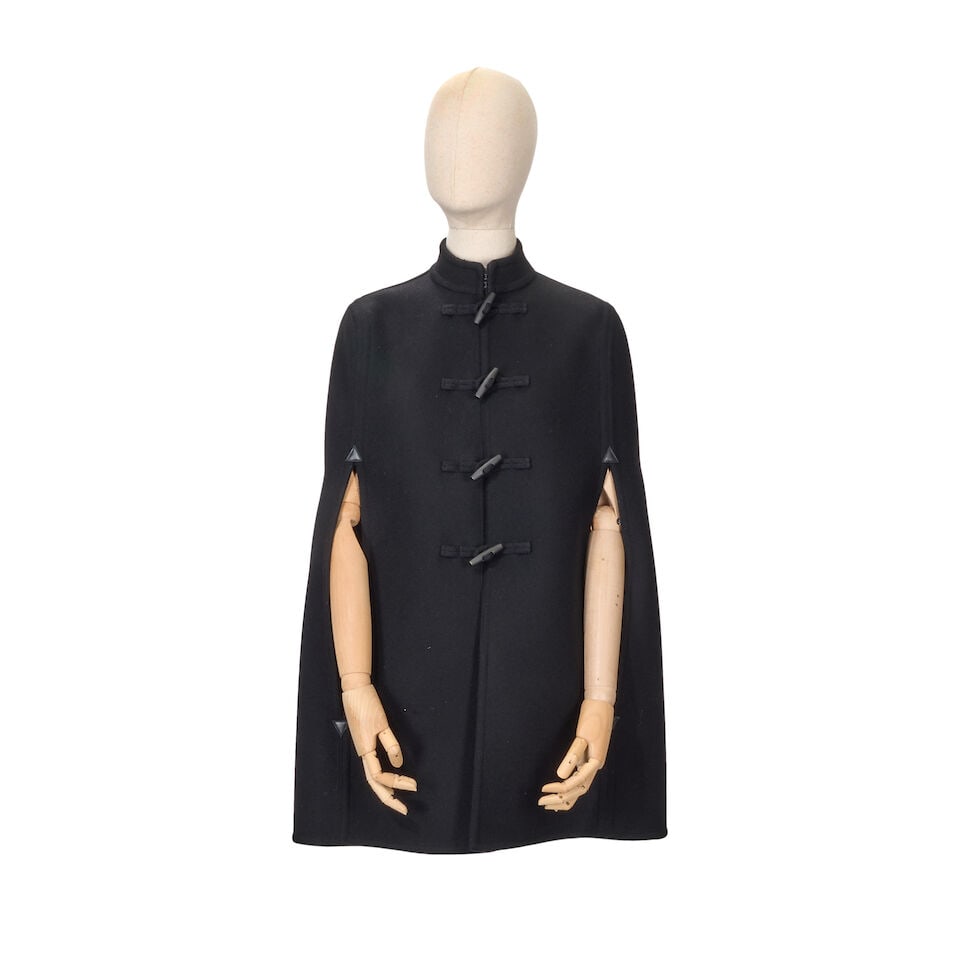 Saint Laurent: a Black Virgin Wool Cape: Saint Laurent: a Black Virgin Wool Cape Felted black unlined wool with toggle fastening and leather details at the arm slits Condition Grade A Labelled size 36 For further information on this lot plea