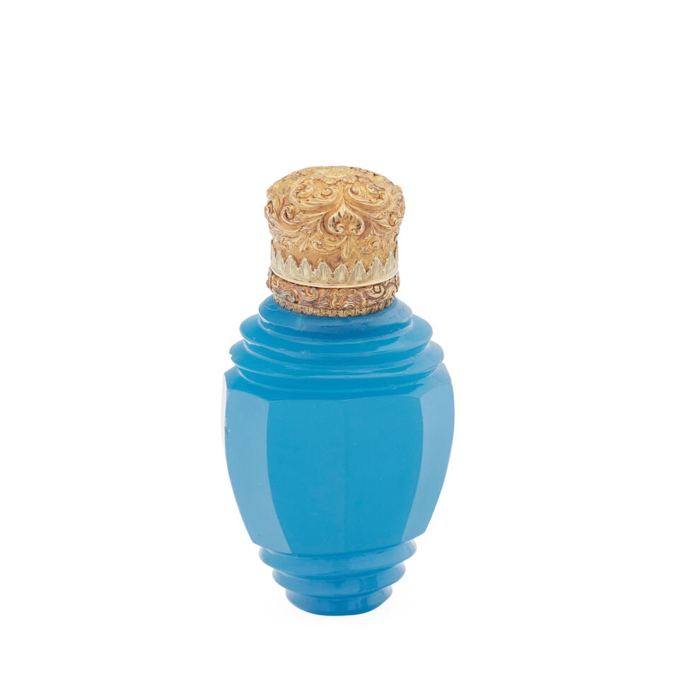 A French gold-mounted blue glass scent bottle circa 1850, unmarked: A French gold-mounted blue glass scent bottle circa 1850, unmarked Of flattened and facetted ovoid form, the hinged cover with scrolling foliage opening to reveal a glass stopper, untested, 7cm high, 