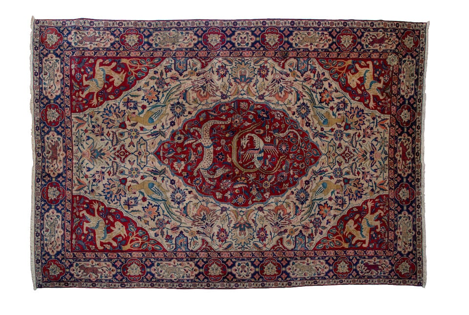 A Tabriz carpet with red medallion North West Persia 360 x 242cm.: A Tabriz carpet with red medallion North West Persia The ivory field with centred red lozenge, woven with birds, animals and scrolling foliage, signed to one corner, within triple borders with alterna