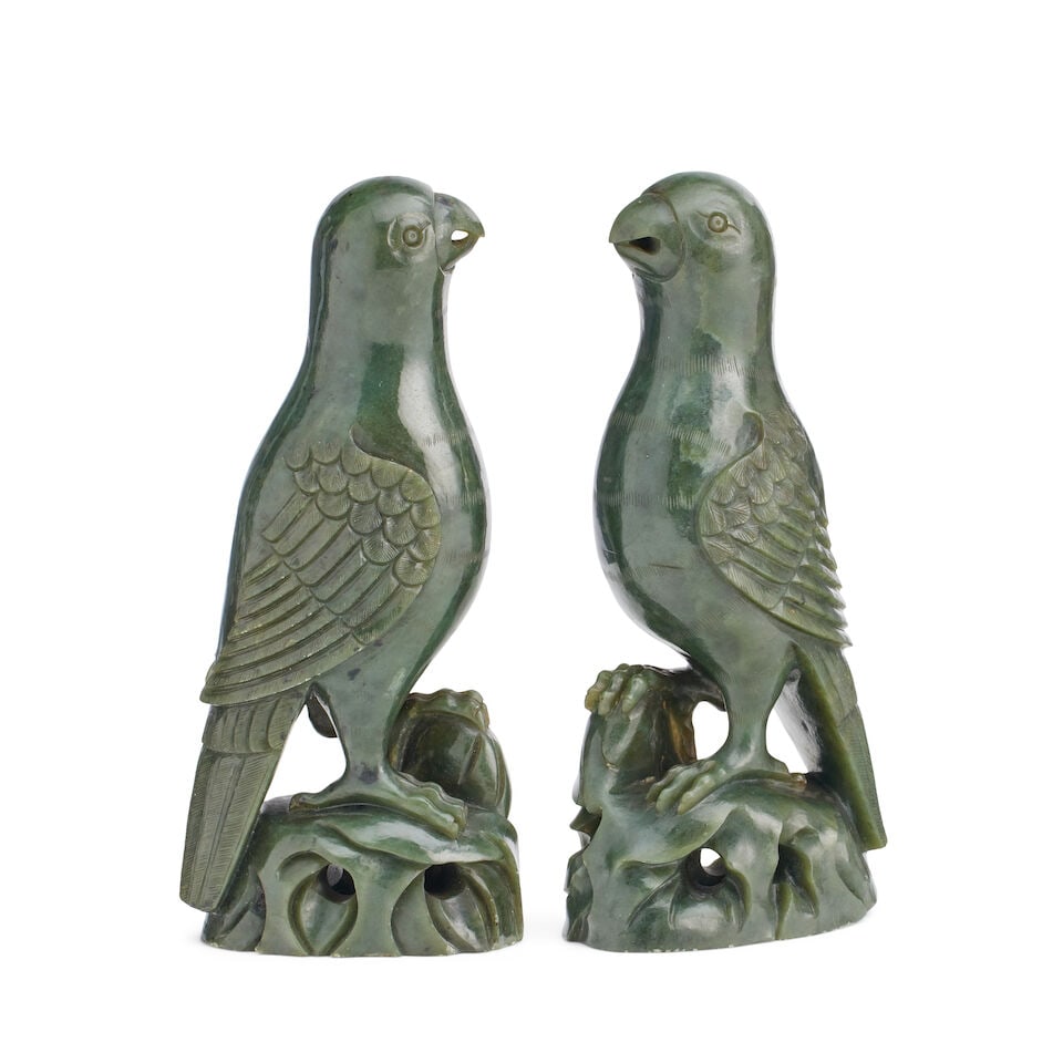 A pair of carved nephrite jade parrots 20th century: A pair of carved nephrite jade parrots 20th century After Kangxi originals and of spinach green tone, shown perched on an oval rocky outcrop, 20cm high For further information on this lot please visit