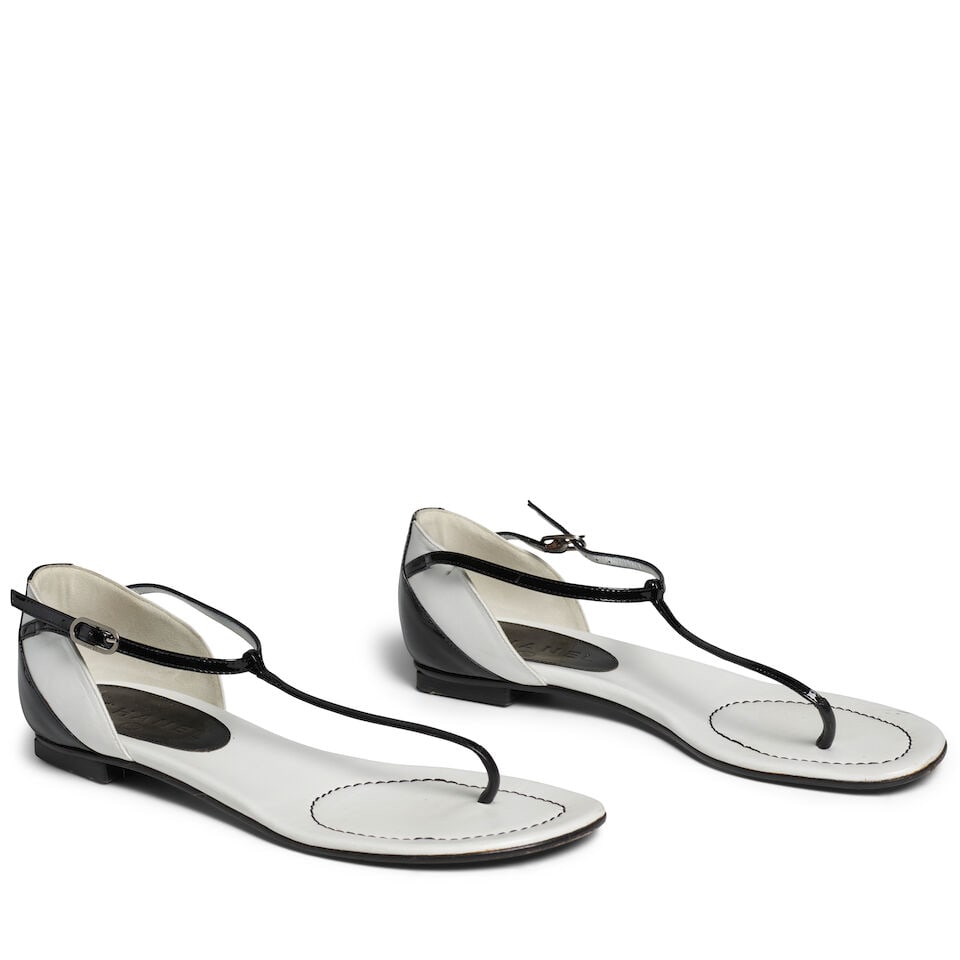 CHANEL: BLACK AND WHITE LEATHER THONG SANDALS: CHANEL: BLACK AND WHITE LEATHER THONG SANDALS • White Leather and Black Patent Leather Exterior • Interlocking CC Logo at Heel • Buckle Closure • Size Marked 38.5 For further i