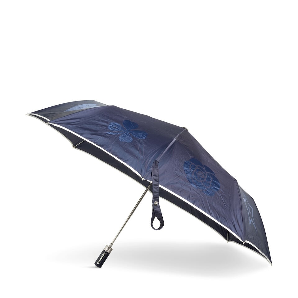 CHANEL: NAVY PRECIOUS SYMBOLS UMBRELLA Early 2000's: CHANEL: NAVY PRECIOUS SYMBOLS UMBRELLA Early 2000's • Navy Exterior with White Trim • Precious Symbol Embossing on Each Panel of Canopy • CC and Chanel Logo Detail on Handle and Tie 