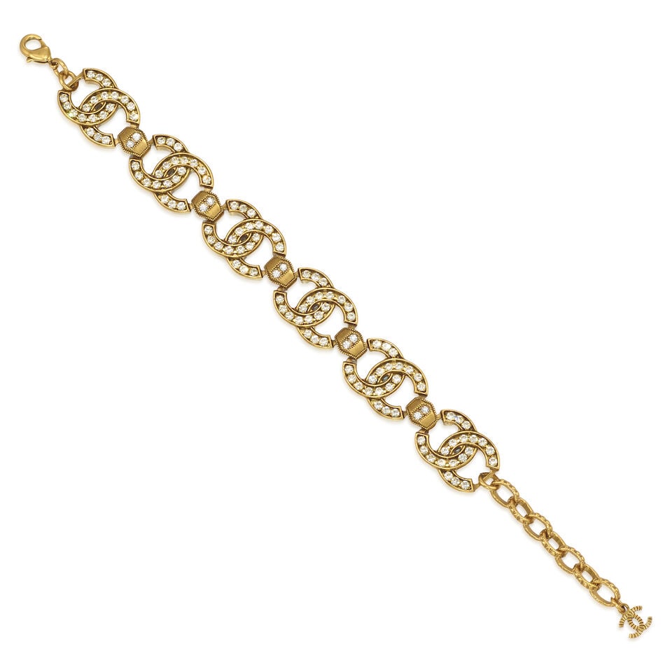 CHANEL: CC LOGO STRASS BRACELET Fall 2021: CHANEL: CC LOGO STRASS BRACELET Fall 2021 • Antiqued Gold Plated Interlocking CC Logos with Strass Embellishment Detail • Adjustable Lobster Closure • Measures 17 cm - 20 cm Length x
