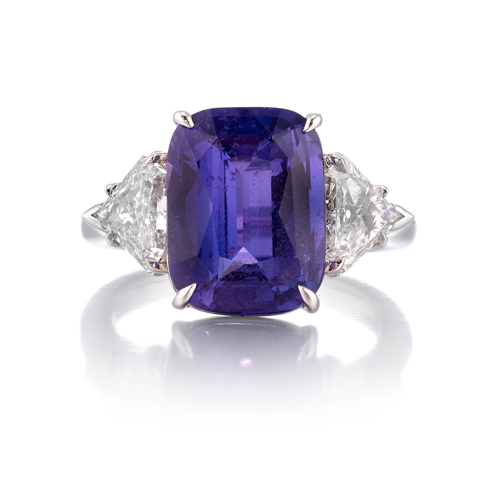 A PLATINUM, PURPLE SAPPHIRE AND DIAMOND RING: A PLATINUM, PURPLE SAPPHIRE AND DIAMOND RING Centering a rectangular cushion-shaped, mixed-cut purple sapphire, weighing 7.06 carats, flanked by trilliant-cut diamonds; estimated diamond weight 0.65